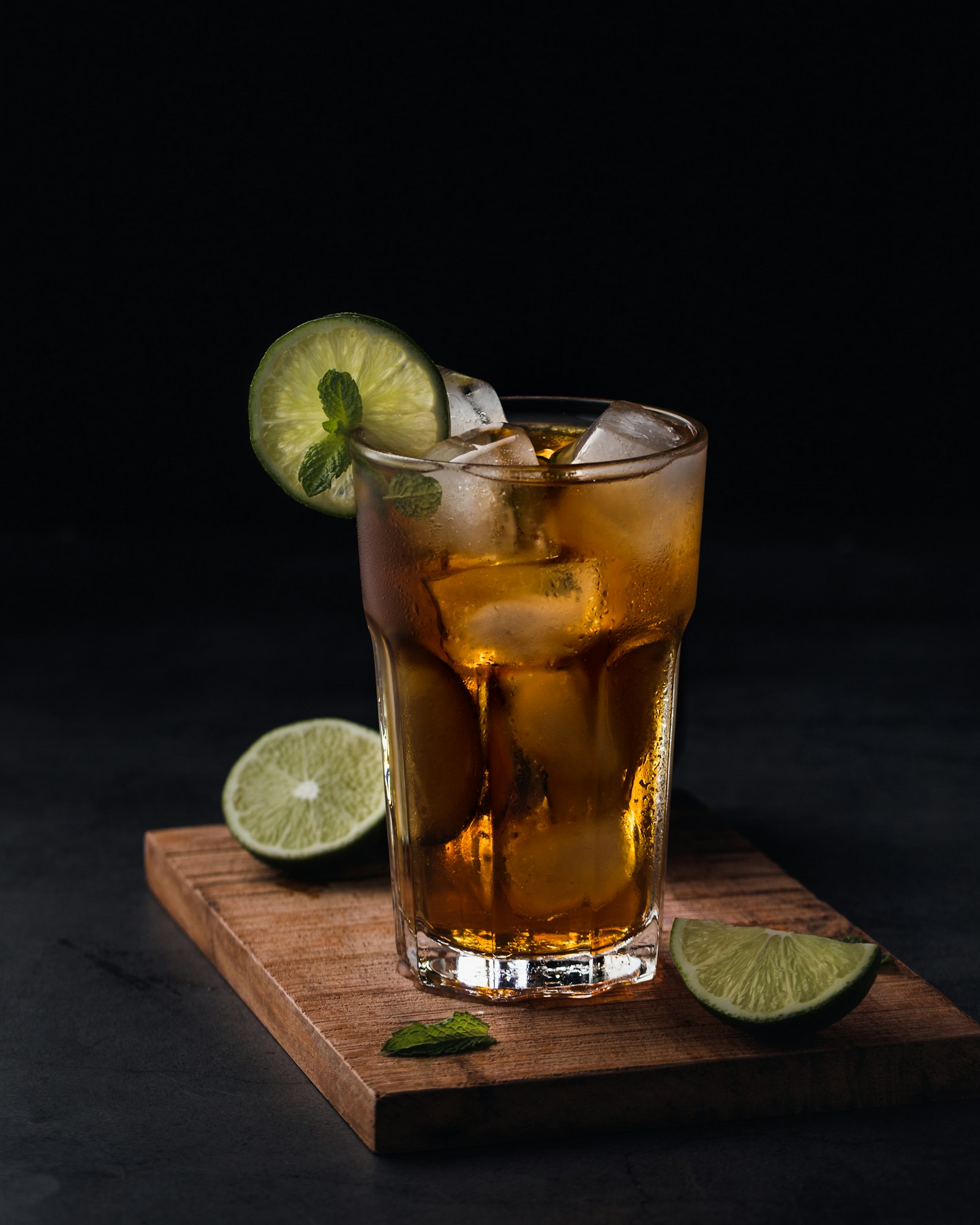 Amber highball with a lime wheel and mint on a cutting board