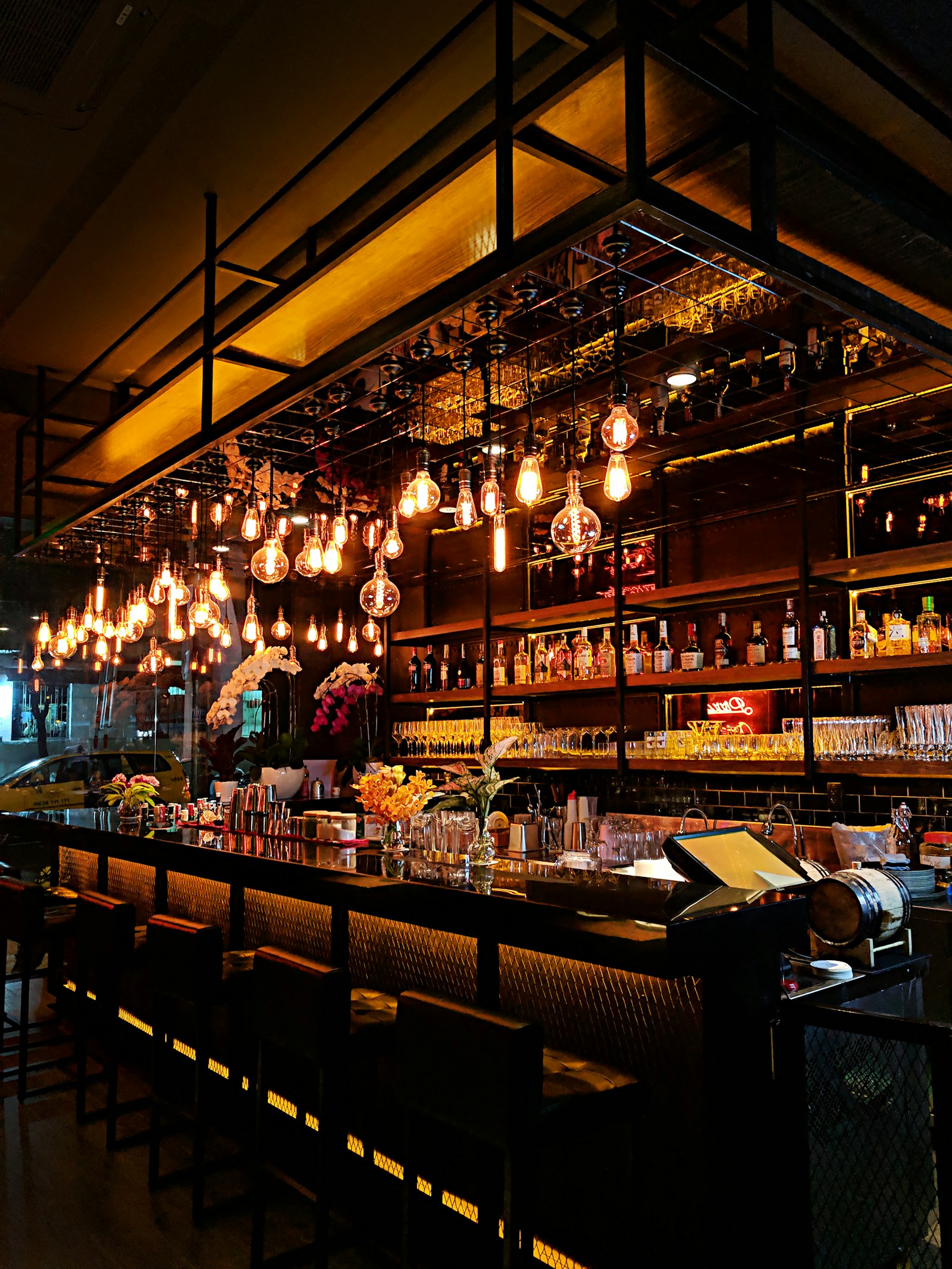 Dark cocktail bar with hanging Edison bulbs and empty stools