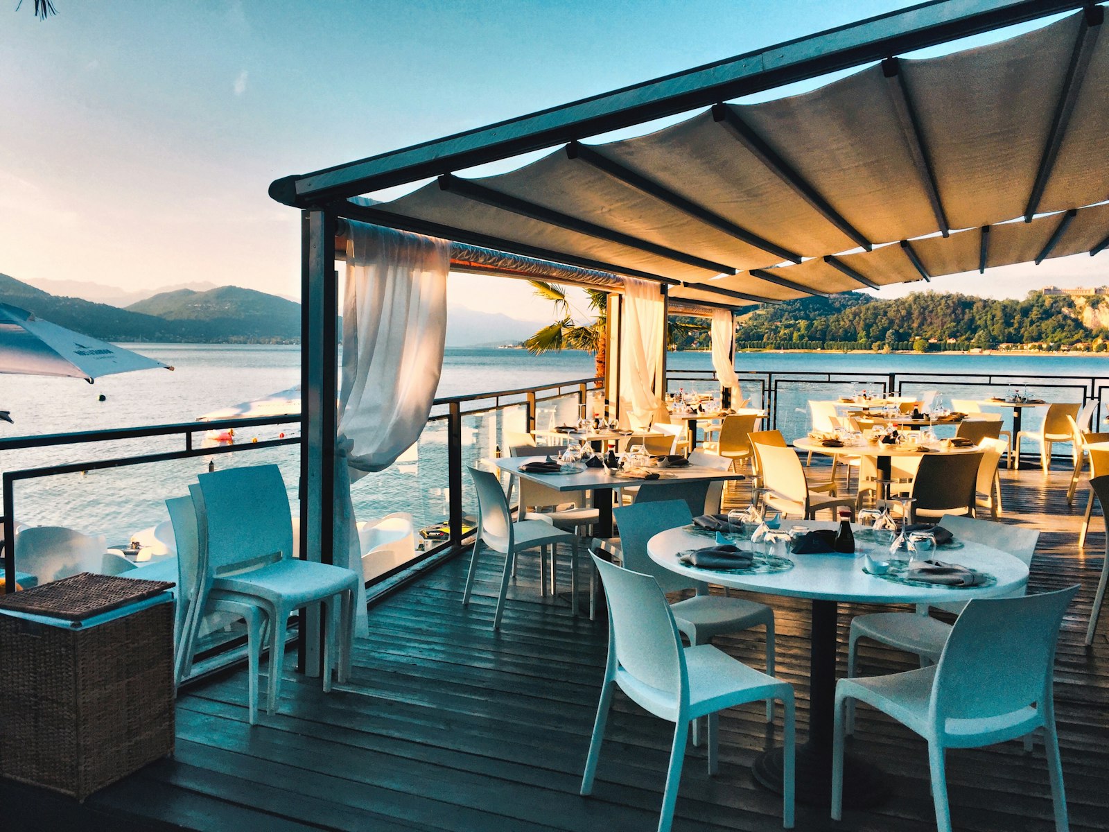 Lakeside restaurant terrace with white tables under a canopy