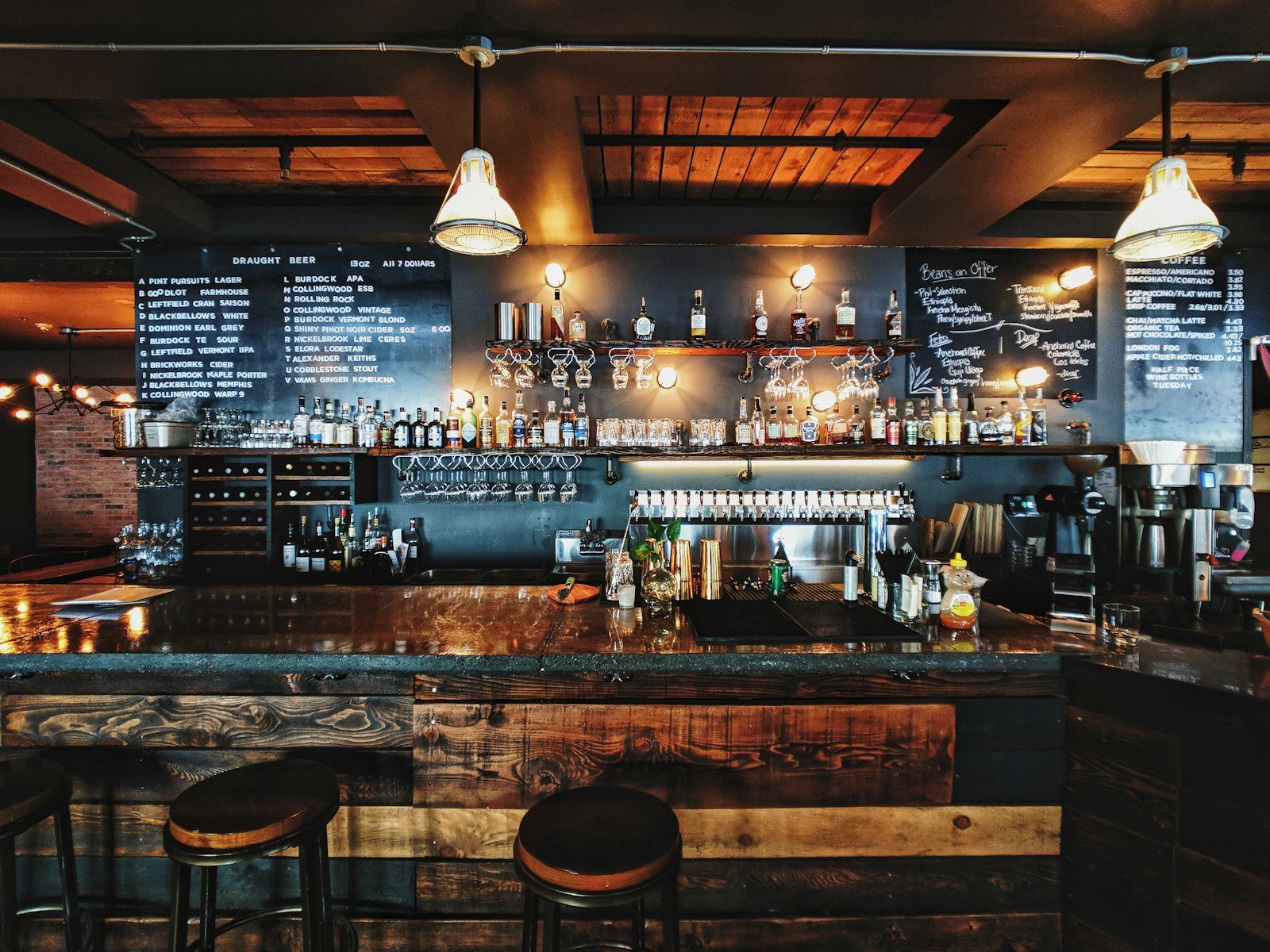 Empty wooden bar with stools, beer taps, and hanging pendant lights