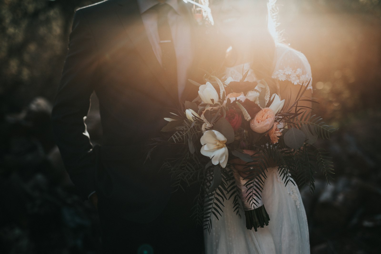 Bride holding a white and blush bouquet beside a groom in a dark suit